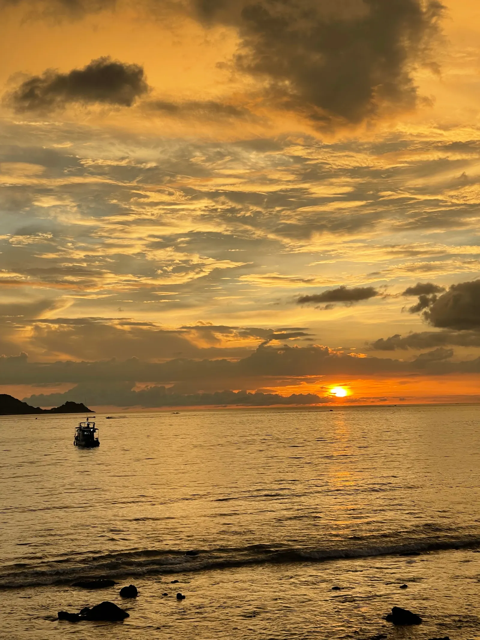 Sunset at Kalim Beach, north of Patong, a longtail on the water