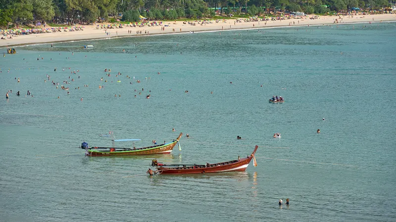 Kata Beach from above: turquoise water, swimmers and two longtail boats off the sand